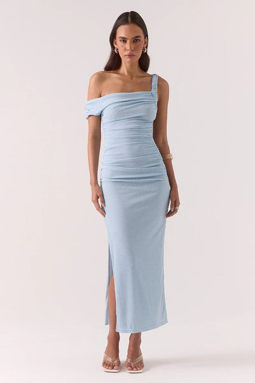 Woman wearing a light blue off-shoulder dress with a slit on a white background