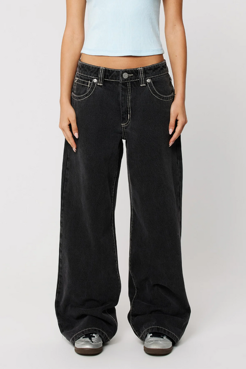 Woman wearing baggy black jean and blue baby tee with sneakers