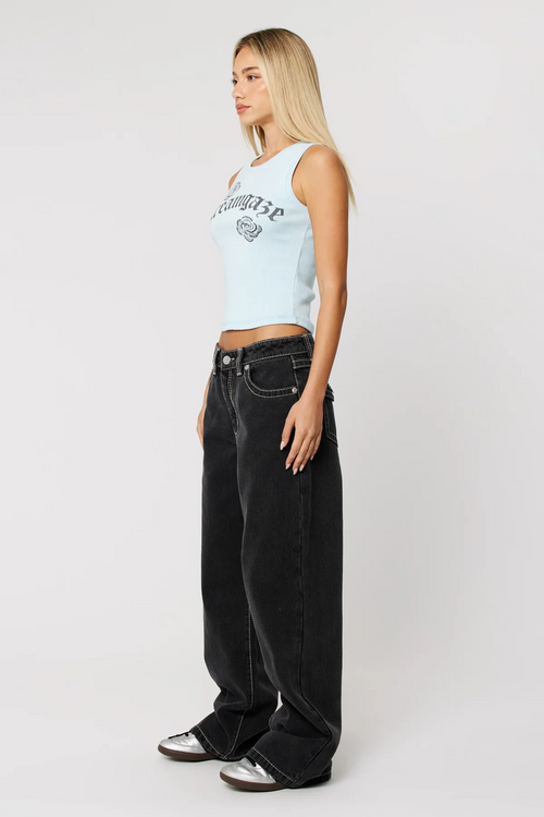 Woman wearing baggy black jean and blue baby tee with sneakers