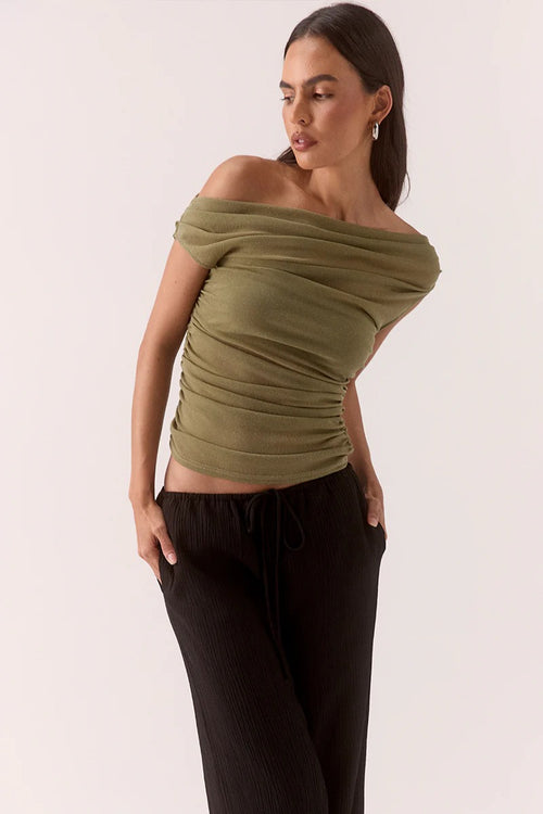 Woman wears a green ruched top and black pants