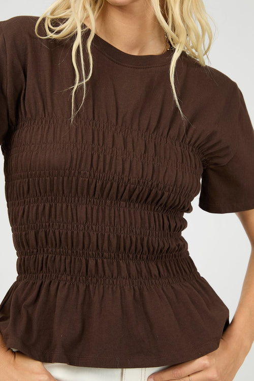 Woman wears a brown ruched top