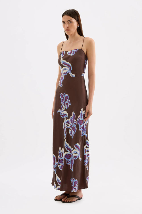 Brown floral maxi slip dress with thin straps, featuring a blue and cream abstract floral print and a straight neckline.