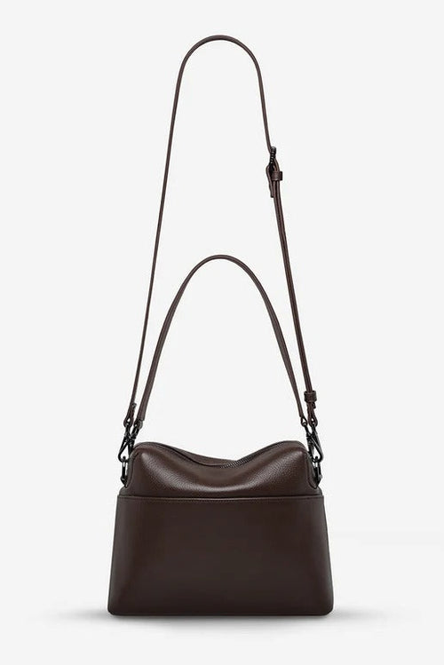 A dark brown leather shoulder bag with a long adjustable strap, displayed against a clean, light gray background.