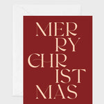 A square Christmas greeting card with a deep red background and elegant cream-colored text reading 'MERRY CHRISTMAS', shown with a white envelope behind it on a light gray background.