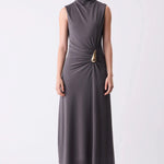 Woman wearing a sleeveless gray dress with a gold belt on a white background