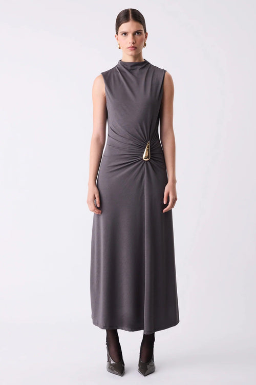 Woman wearing a sleeveless gray dress with a gold belt on a white background