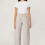 A woman modeling a white short-sleeve crewneck t-shirt and light beige wide-leg cropped trousers, paired with dark gray pointed-toe flats, against a plain off-white studio background.