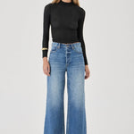 Woman wearing a black top and blue jeans on a white background