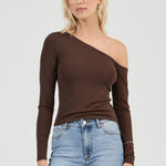 Woman wearing a brown one-shoulder top and blue jeans on a white background