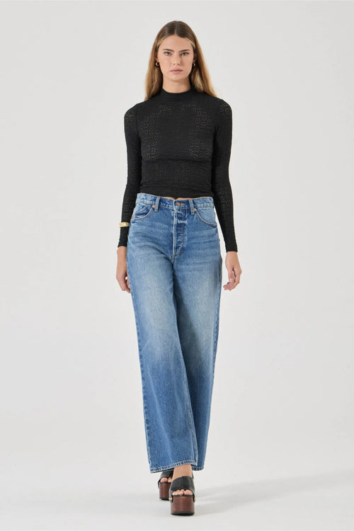 Woman wearing a black sweater and blue jeans on a white background