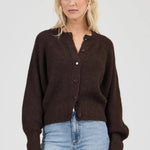 Woman wearing a brown cardigan and light blue jeans on a white background