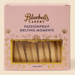 A pink box of Bluebell's Cakery Passionfruit Melting Moments, featuring a clear window that displays the golden-brown biscuit slices inside, set against a solid cream background.