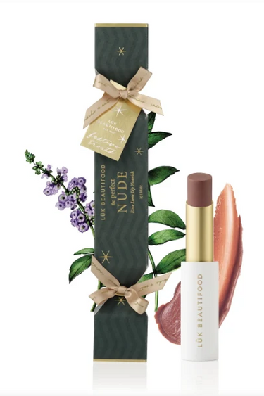 Luk Beautyfood No.06 Nude Lipstick shown with its dark green gift box decorated with gold stars, a beige ribbon, and botanical illustrations, alongside the lipstick tube and two lipstick color swatches on a white background.