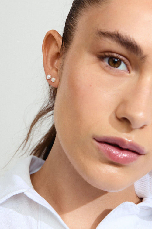 Close-up of a woman wearing a small earring on a plain background