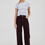 Woman wearing a light gray t-shirt and dark brown corduroy pants on a white background