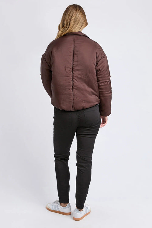Person wearing a brown puffer jacket and black pants on a white background
col_pattern