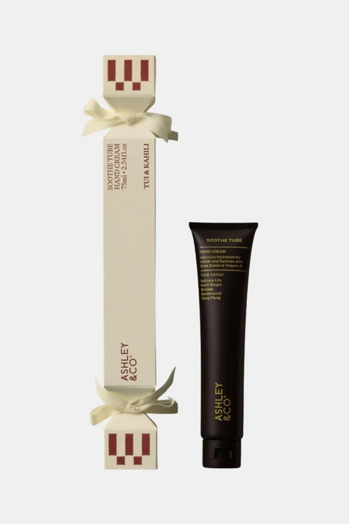 Asley & Co. Hand Cream shown with its cream-colored gift box tied with a white ribbon and a black squeeze tube with gold lettering, on a light gray background.