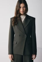 Woman wearing a dark gray suit against a white background