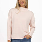 Woman wearing a light pink sweater and blue jeans on a white background