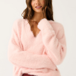 Woman wearing a pink fluffy sweater and red pants on a white background
