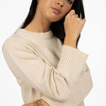 Woman wearing a beige sweater against a white background