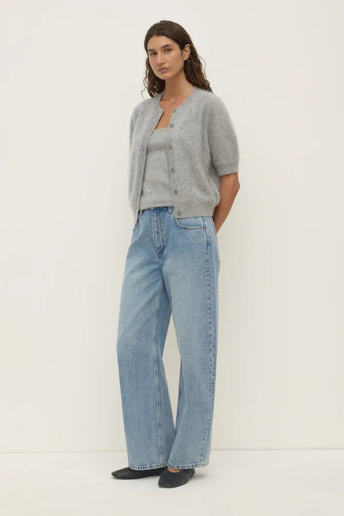 Woman wearing a gray cardigan and light blue jeans on a white background