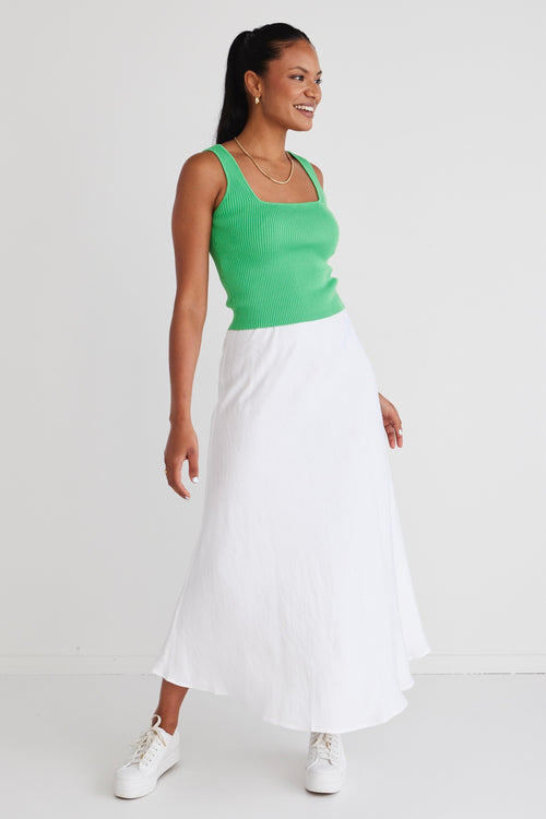 model wears a green top and white linen skirt