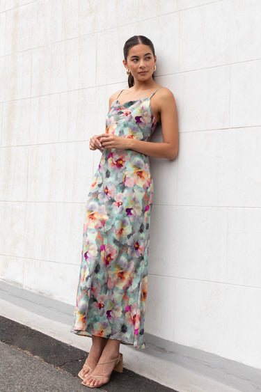 Model wears a blue floral maxi dress with a tie back and adjustable straps
