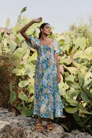 model is outside and wears and blue and orange floral maxi dress with sandals