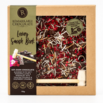 A boxed chocolate bar set from Remarkable Chocolate, featuring a kraft paper package with a clear window showing dark chocolate pieces mixed with red berries and white chocolate shavings.