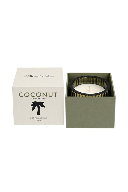A scented candle in an open square box next to its white outer packaging. The candle has a white wick and a ribbed dark green outer ring, while the box is white with green text reading 'Willow & Mae' and 'COCONUT'.