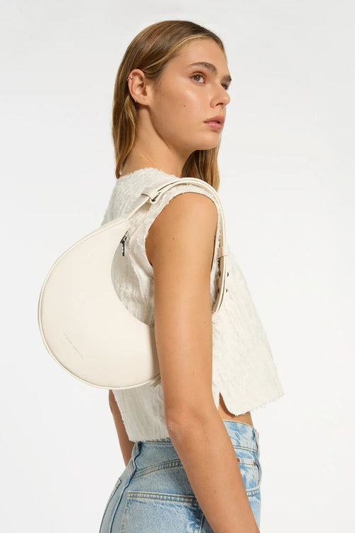 Woman holding a white handbag against a plain background