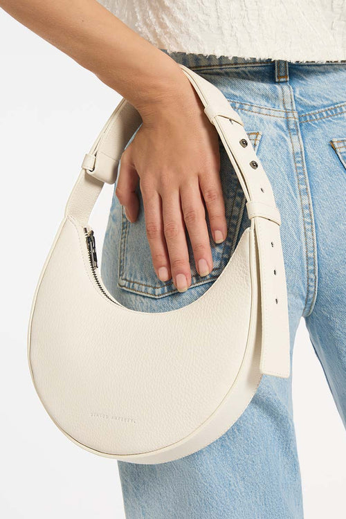 Person holding a white handbag with light blue jeans