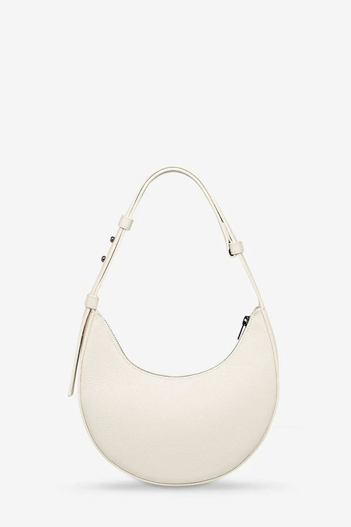 An off-white crescent-shaped leather shoulder bag with a single adjustable strap, displayed against a clean, light gray background.