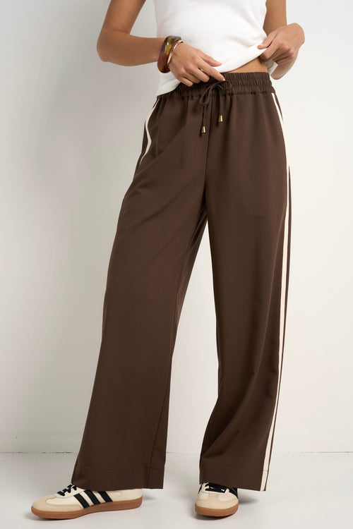 Model wears brown track pants