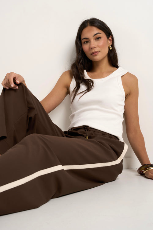 Model wears brown track pants