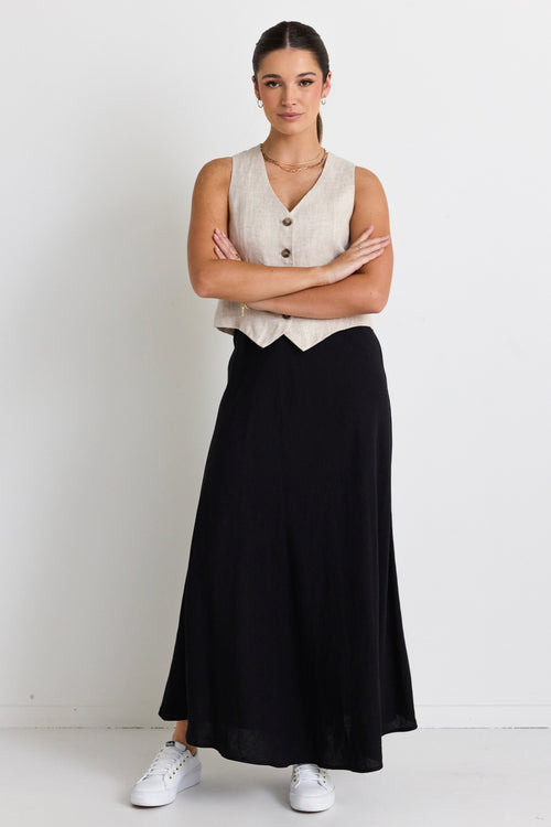 model wears linen vest and black linen maxi skirt with white sneakers