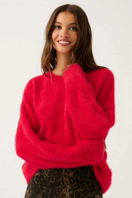 Woman wearing a bright pink sweater with a white background