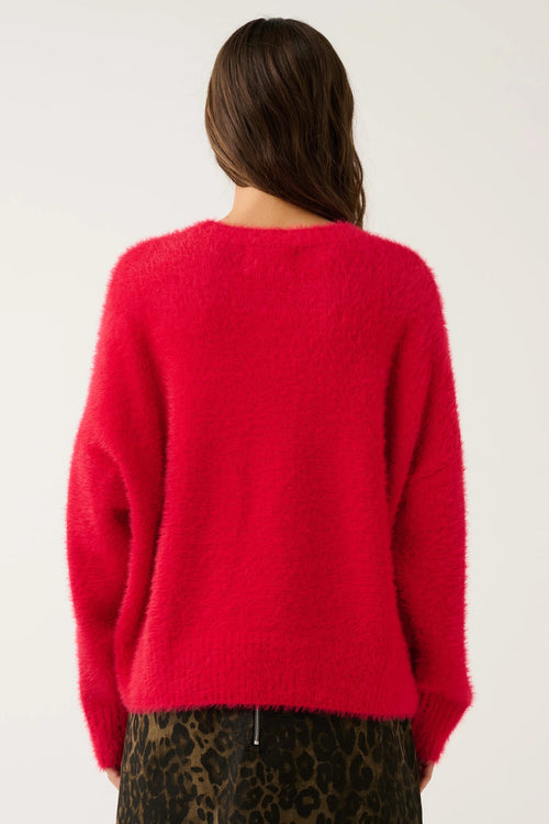 A model shown from the back wearing a bright red fuzzy knit sweater and a brown leopard print skirt against a plain light gray background.