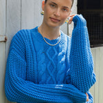 model wears a blue cable knit with black pants