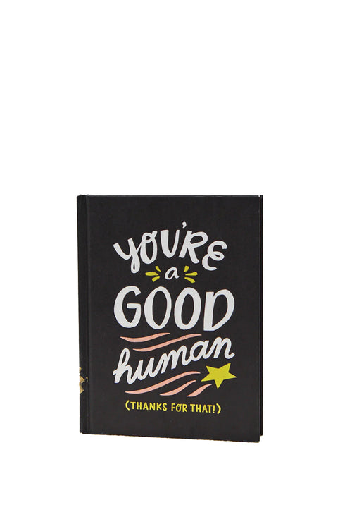 Black notebook with 'You're a good human' text on a white background